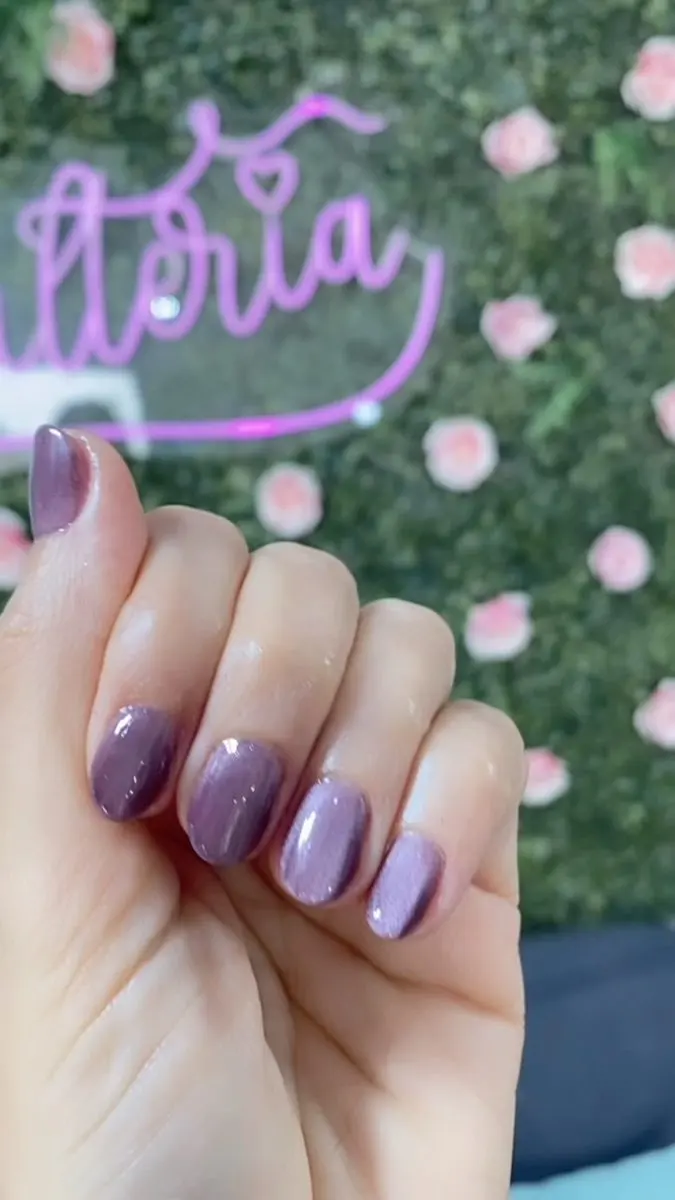 Unhas lilás diante da parede de flores